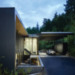The Wood Block residence is a clean, modern design. There is a pool in the foreground with an open area, exposed concrete, and floor to ceiling windows.