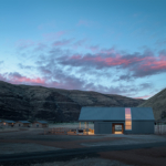 Exterior view of the Cottonwood Canyon Experience Center, showcasing a modern architectural design that harmonizes with the surrounding natural landscape. The building features large windows, a wooden facade, and a sloped roof, creating an inviting and functional space. The setting includes landscaped areas with native plants, emphasizing the center's connection to the environment and its role as an educational facility.