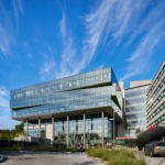 Exterior view of the Seattle Children's Building, showcasing a modern architectural design with large glass windows, a welcoming entrance, and landscaped surroundings. The building features a combination of brick and metal materials, with a bright and inviting facade that reflects a child-friendly environment.